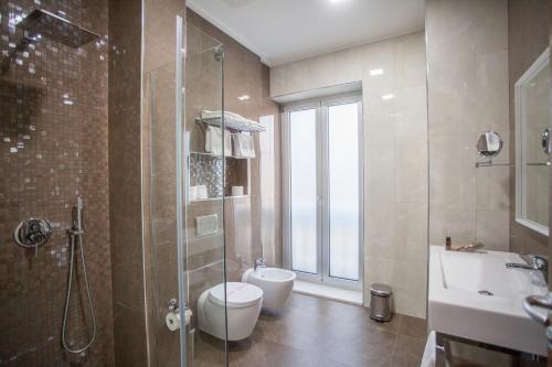 a bathroom with a shower and a toilet and a sink at Hotel Colosseo Tirana in Tirana