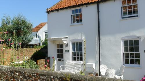 a white house with white chairs in front of it at Loom Cottage in Southwold
