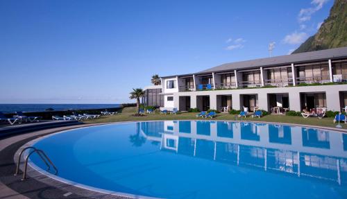 a hotel with a large swimming pool next to the ocean at Estalagem do Mar in São Vicente