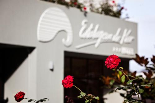 a white building with red flowers in front of it at Estalagem do Mar in São Vicente