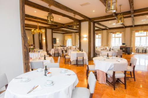 Un comedor con mesas y sillas blancas. en Parador de Ribadeo, en Ribadeo