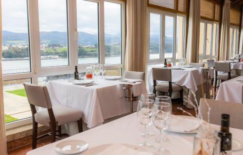 a restaurant with white tables and chairs and windows at Parador de Ribadeo in Ribadeo