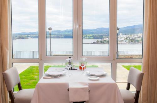 a table with a white tablecloth and chairs in front of windows at Parador de Ribadeo in Ribadeo