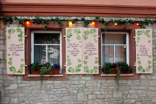 a building with three windows with flowers and lights at Hotel Altdeutsche Weinstuben in Freyburg