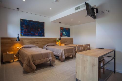 a room with three beds and a table and a television at Hotel La Tavernetta in Campobasso