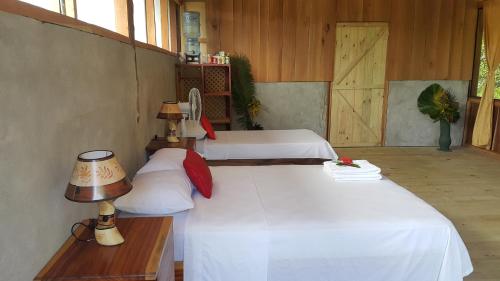 a bedroom with two beds with white sheets and a lamp at Casa Drake Lodge in Drake
