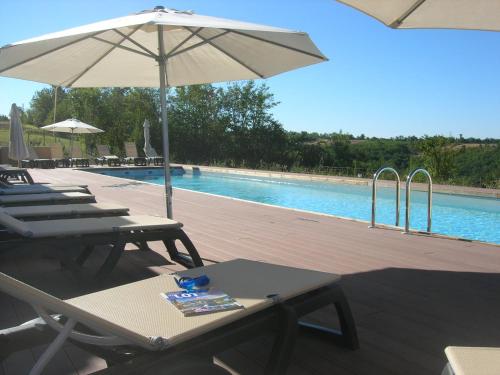 uma piscina com espreguiçadeiras e um guarda-sol em Les Hauts d'Albas em Albas