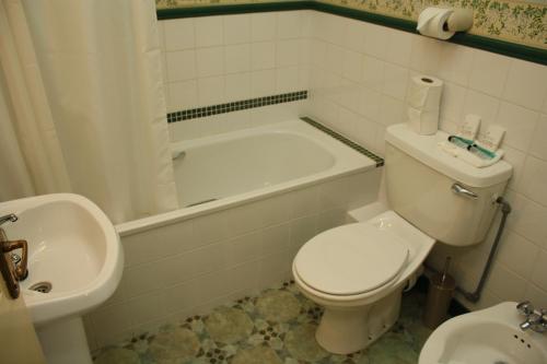 a bathroom with a toilet and a tub and a sink at Woodhill House in Ardara