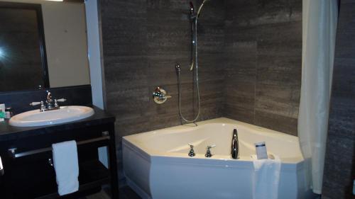 a bathroom with a bath tub and a sink at Grand Times Hotel Sherbrooke in Sherbrooke