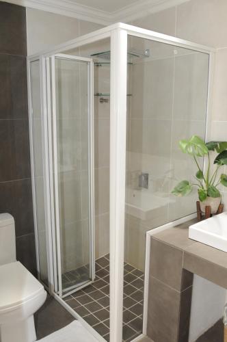 a bathroom with a shower and a toilet and a sink at Hilken Lodge in Durban