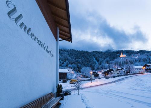 a building with snow on the ground next to a town at Michelerhof - kinderfreie Unterkunft in Lavant