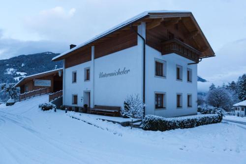 a white building with a wooden roof in the snow at Michelerhof - kinderfreie Unterkunft in Lavant