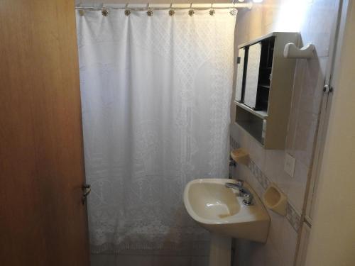 a bathroom with a white shower curtain and a sink at La Loberia - Las Grutas in Las Grutas