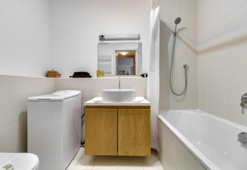 a bathroom with a sink and a toilet and a tub at Quality Point Apartments 0-24 reception in Budapest