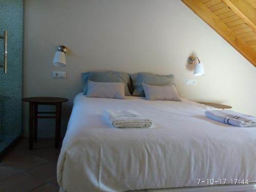 a bedroom with a large white bed with towels on it at Tu casita de la Senda del Oso in Proaza