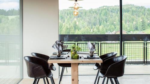 uma mesa de jantar com cadeiras pretas em frente a uma janela em Naturhotel Pfösl em Nova Ponente