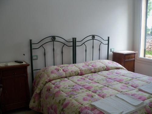 a bedroom with a bed with a floral bedspread and a window at Agriturismo Il Pavone in Torre Lapillo
