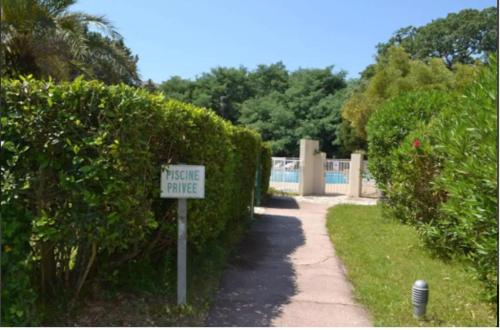a hedge fence with a sign next to a walkway at Eden in Saint-Tropez