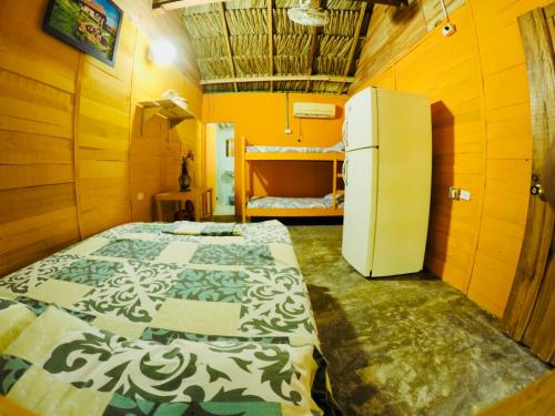 a bedroom with a bed and a refrigerator in it at Cabañas Ecoturisticas Y Club Gaira Tayrona in Santa Marta