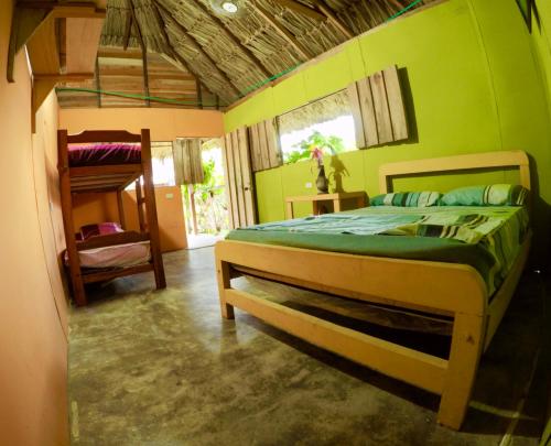 a bedroom with a bed with a green wall at Cabañas Ecoturisticas Y Club Gaira Tayrona in Santa Marta