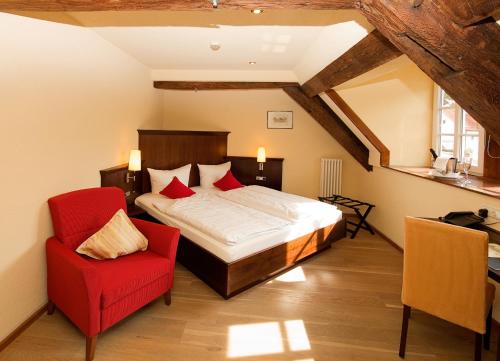 a bedroom with a bed and a red chair at Hotel Restaurant Ölmühle in Landstuhl