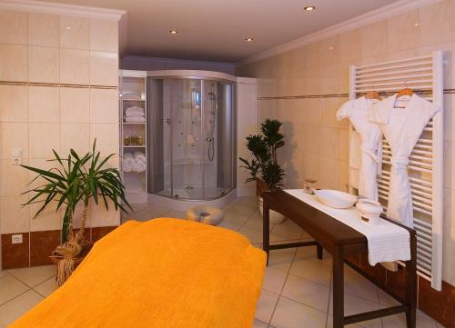 La salle de bains est pourvue d'une douche, d'une table et d'un lavabo. dans l'établissement Hotel Restaurant Ölmühle, à Landstuhl
