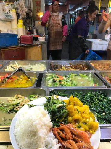 a buffet of food with rice and vegetables in trays at Books&Bed Close to the Lake in Hangzhou