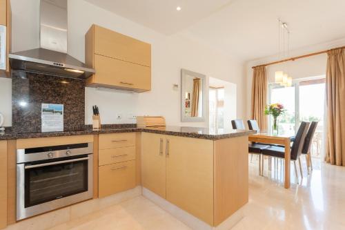 a kitchen with wooden cabinets and a dining room at Arcos Gardens Sol Rent Golf in Arcos de la Frontera