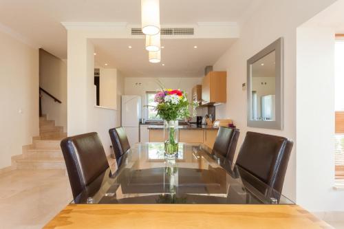 a dining room table with chairs and a vase of flowers at Arcos Gardens Sol Rent Golf in Arcos de la Frontera