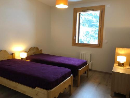 ヴォジャニーにあるDomaine du Patreの紫のシーツを使用したベッド2台、窓が備わる客室です。