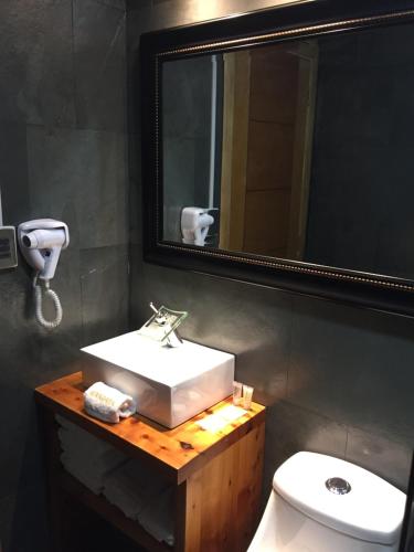 a bathroom with a sink and a mirror and a toilet at Mangata Hotel Low Cost in Castro