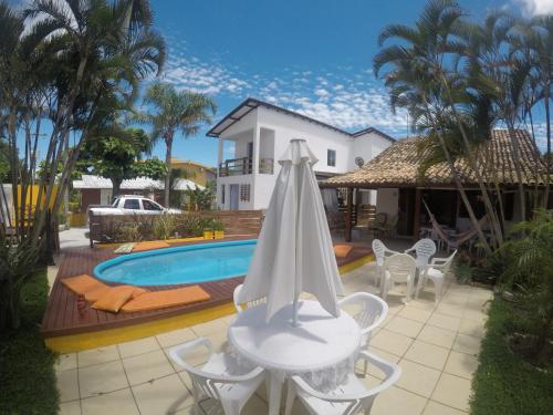 - un parasol blanc assis sur une terrasse à côté d'une piscine dans l'établissement Casa Pousada Rosa dos Ventos, à Florianópolis