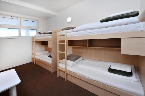 a room with three bunk beds and a desk at Bel Hostel in Tatranská Lomnica