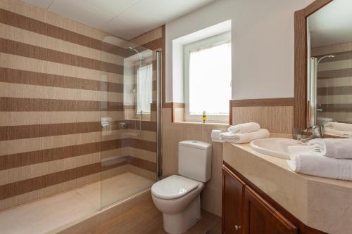 a bathroom with a toilet and a sink and a mirror at Arcos Gardens Sol Rent Golf in Arcos de la Frontera