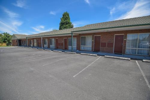 an empty parking lot with a building behind it at Sandown Heritage Motel in Noble Park