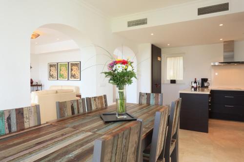 a dining room with a wooden table with a vase of flowers at Arcos Gardens Sol Rent Golf in Arcos de la Frontera