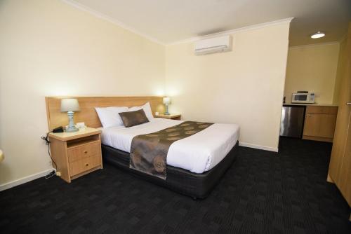 um quarto de hotel com uma cama grande e uma mesa de cabeceira em Sandown Heritage Motel em Noble Park