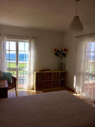 a bedroom with a bed and a view of the ocean at Casa Sol e Mar em Porto Covo in Porto Covo