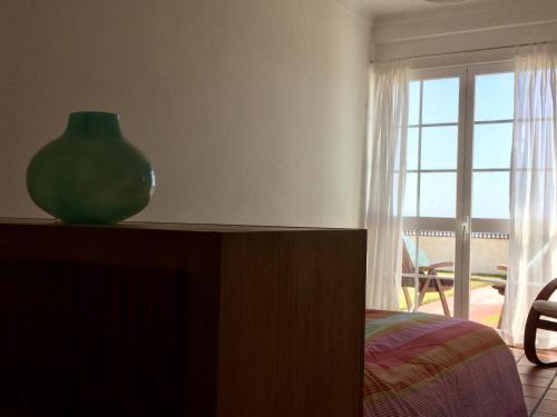 a green vase sitting on top of a dresser next to a window at Casa do Mar em Porto Covo in Porto Covo