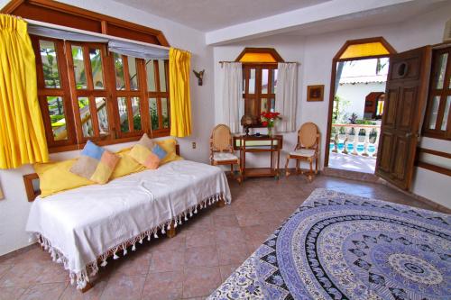 a bedroom with a bed with yellow curtains and a table at Hotel Gilda in Coyuca