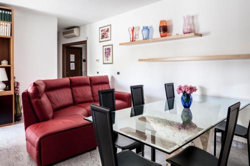 a living room with a glass table and a red couch at Bed & Breakfast Cesarina in Bologna
