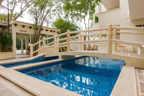 a swimming pool with a wooden rail next to a house at Condo Casa del Arbol in Playa del Carmen