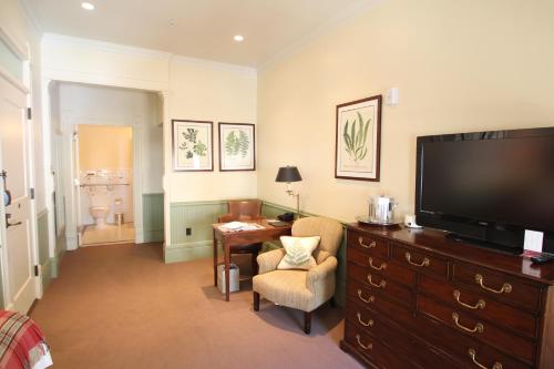 a living room with a television and a desk with a chair at New Sheridan Hotel in Telluride