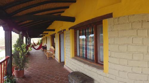 a yellow building with windows and a brick sidewalk at Hotel Spa Casa de Adobe Villa de Leyva in Villa de Leyva