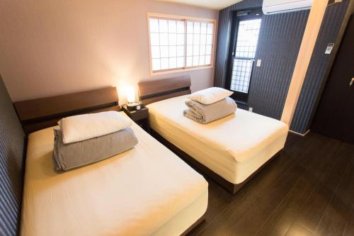 Cette chambre comprend 2 lits et une fenêtre. dans l'établissement Kanesuke Kyoto, à Kyoto