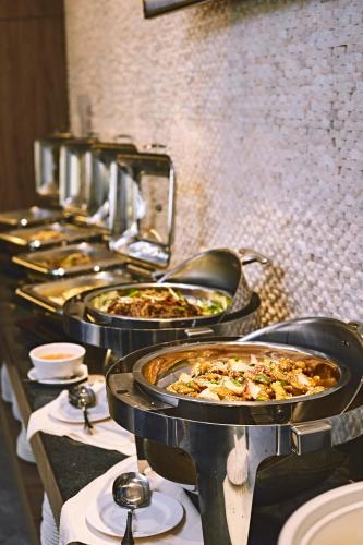 a row of pizzas in pans on a buffet line at Meritin Hotel in Kuching