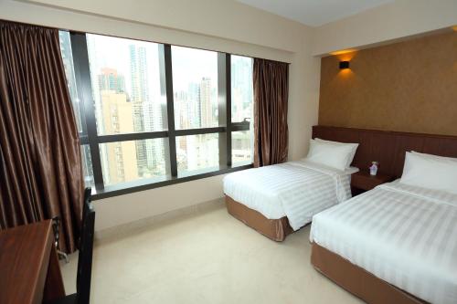 a hotel room with two beds and a large window at WE Hotel in Hong Kong