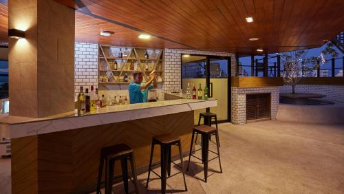a woman standing at a bar with stools at Whale Hua Hin - SHA Plus in Hua Hin