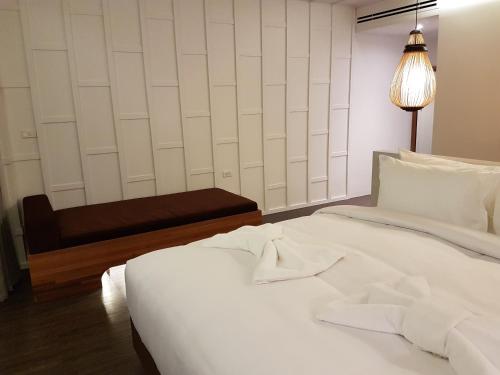 a bedroom with a white bed and a bench at Whale Hua Hin - SHA Plus in Hua Hin
