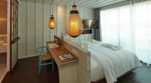 a bedroom with a large bed and a desk with a chair at Whale Hua Hin - SHA Plus in Hua Hin